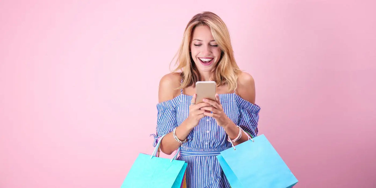 Femme portant des sacs de shopping et son téléphone portable.