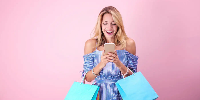 Femme portant des sacs de shopping et son téléphone portable.