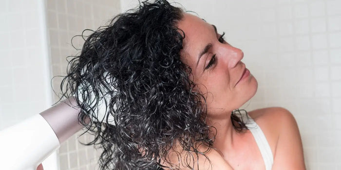 Femme aux cheveux bouclés séchant ses cheveux.