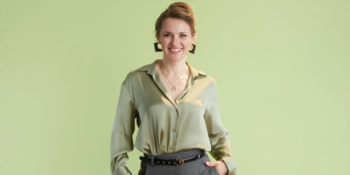 Femme portant un chemisier soyeux vert.