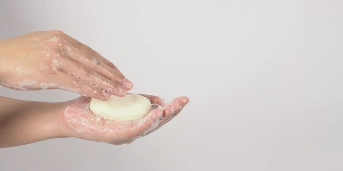 Lavage d'un cache-téton à la main avec du savon doux.