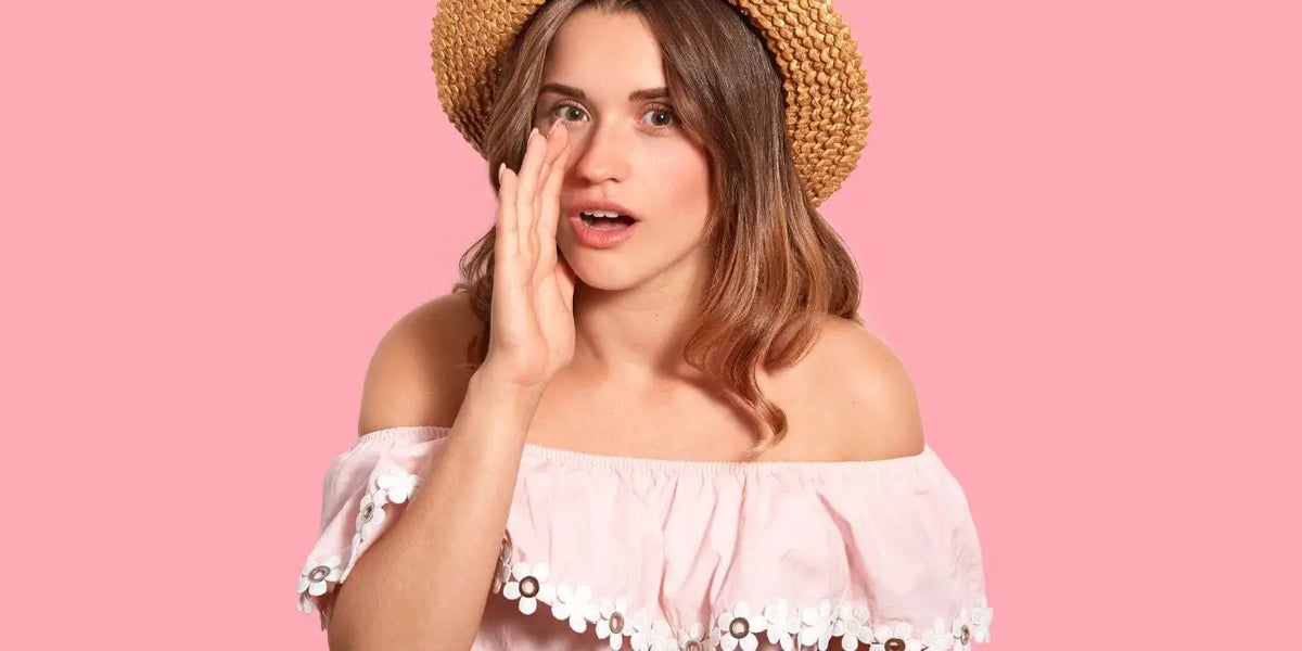 Femme portant une blouse rose et un chapeau de paille.