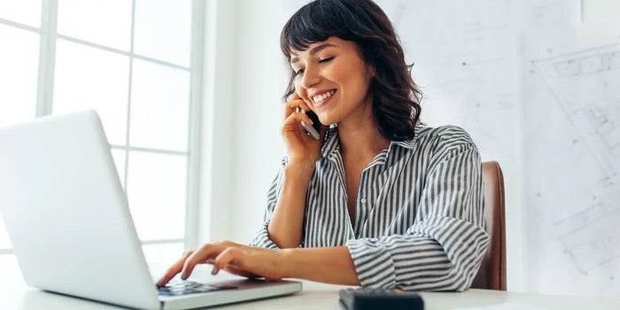 Femme portant une chemise rayée face à son ordinateur de travail.