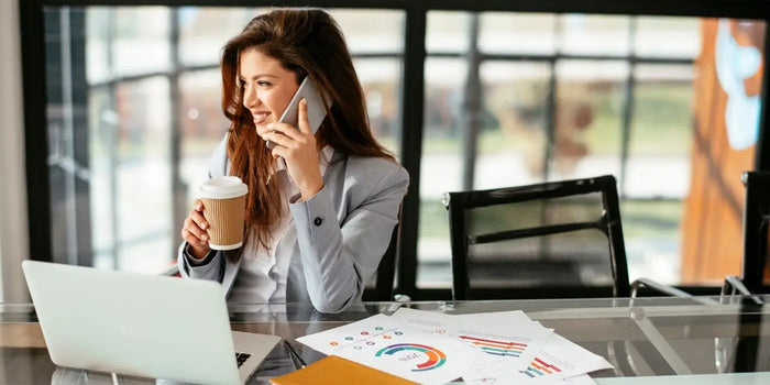 Femme au téléphone, portant une tenue professionnelle au travail.