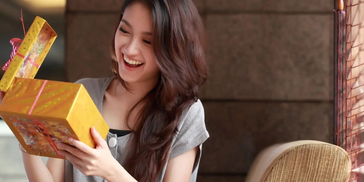 Une femme de 30 ans ouvre un cadeau.