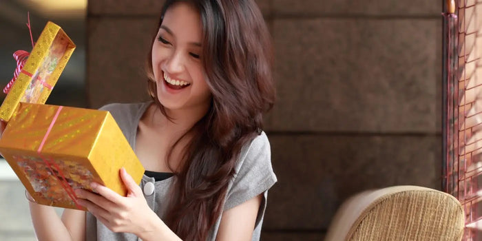 Une femme de 30 ans ouvre un cadeau.