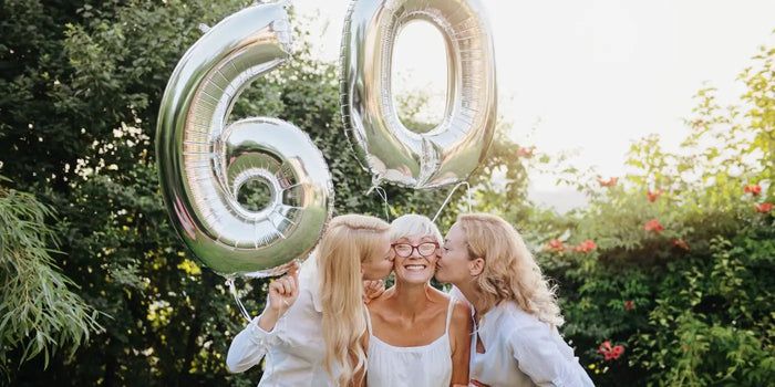 Une femme est entourée par ses filles pour fêter son anniversaire et recevoir des cadeaux pour femme de 60 ans.