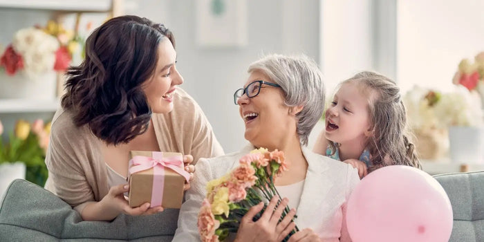 Une femme reçoit des cadeaux de fête des mères de la part de sa fille et de sa petite fiille.