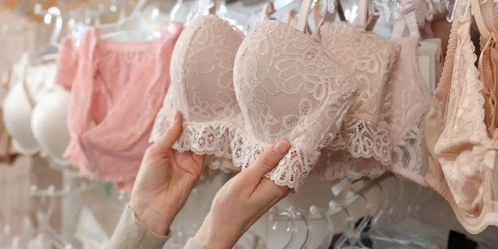 Femme choisissant un soutien-gorge dans un rayon de lingerie en prenant en compte la forme.
