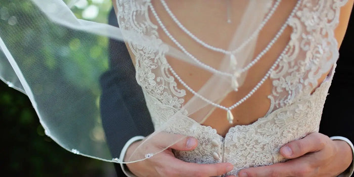 Mariée de dos, voile et collier de dos en perle blanc.