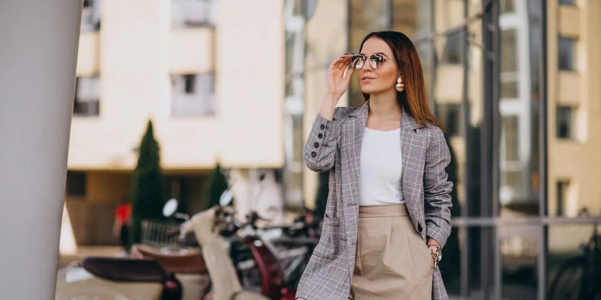 Femme portant un body blanc, un blazer et un pantalon beige.