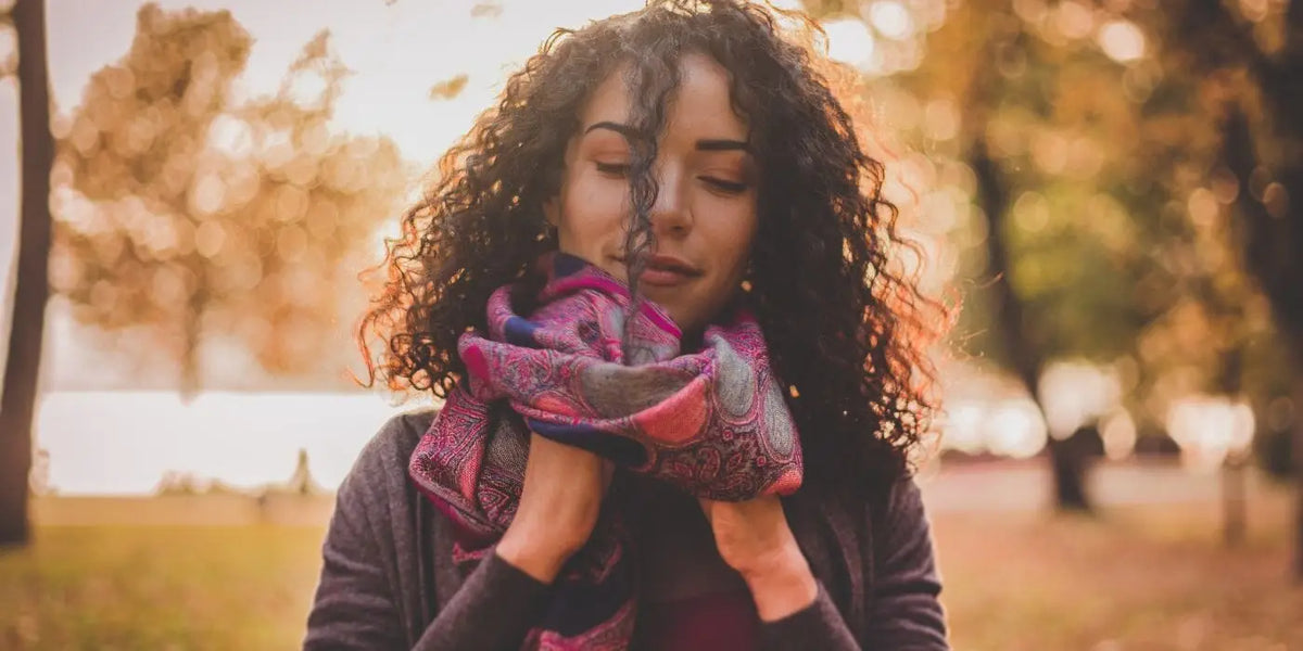Femme portant une écharpe en cachemire dans les tons rose et violet.