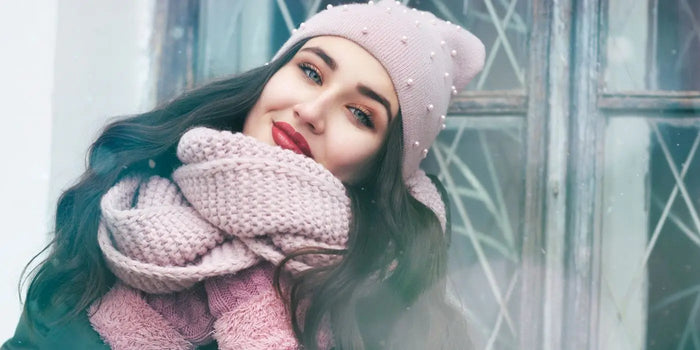 Femme portant une écharpe en grosse maille rose avec un bonnet assorti.