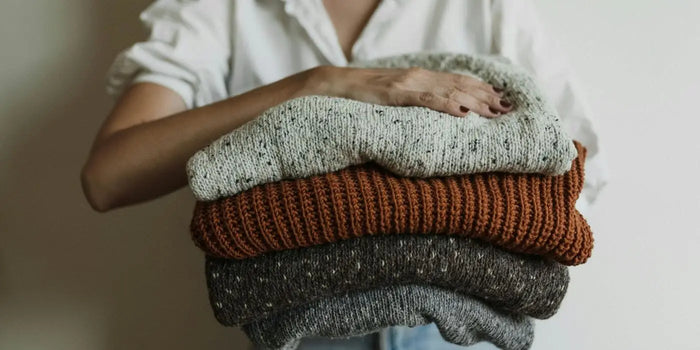 Femme portant une pile de robes pull propres.