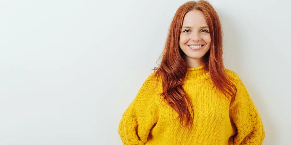 Femme souriante portant un pull jaune col cheminée.