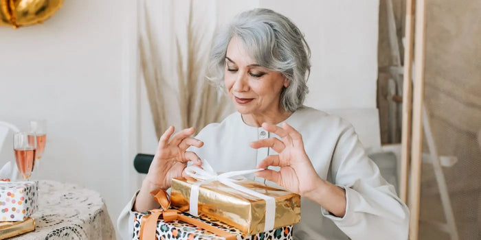 Lors d'une fête, une femme ouvre un cadeau pour ses 70 ans.