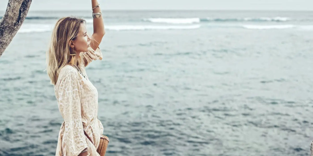 Femme portant une robe bohème face à la mer.