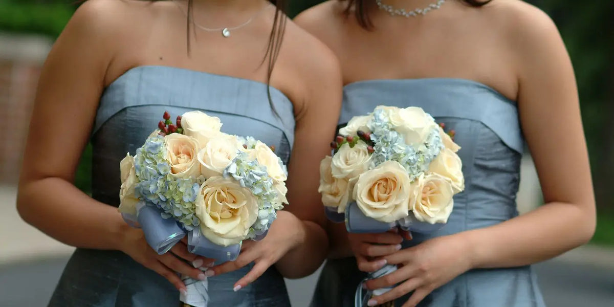 Deux femmes portent une robe bustier et des bouquets de fleurs pour un mariage. 