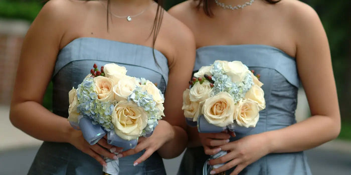 Deux femmes portent une robe bustier et des bouquets de fleurs pour un mariage. 