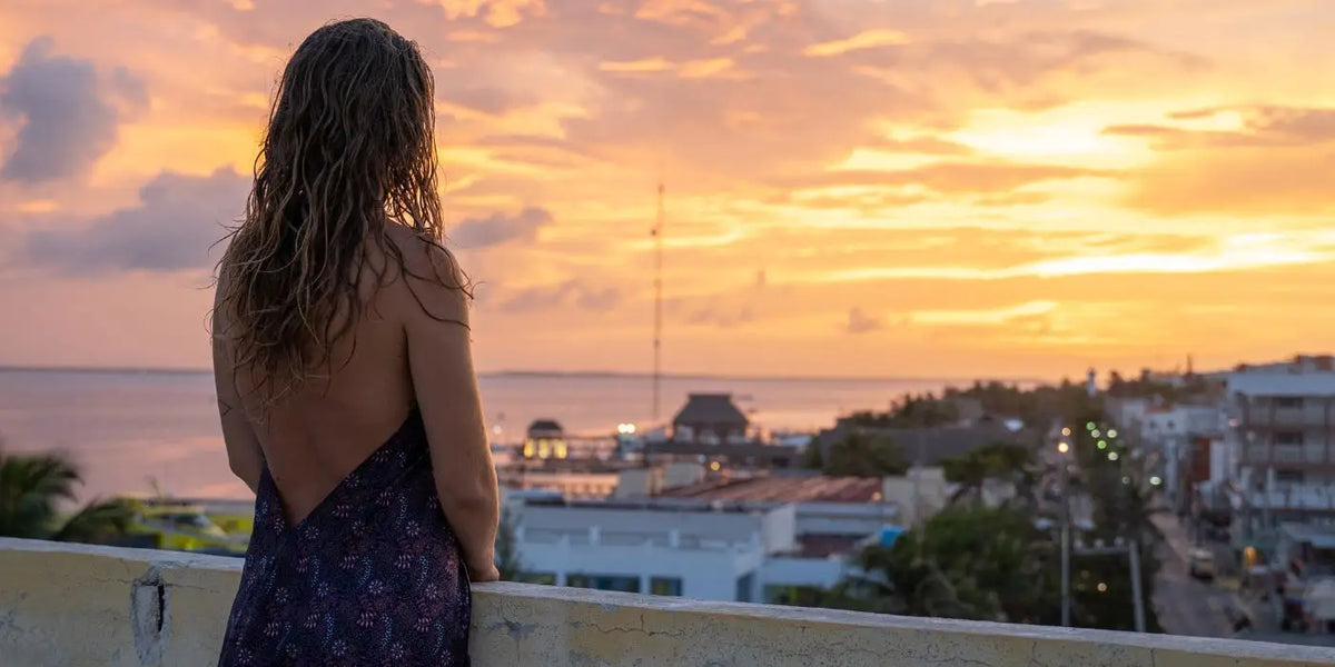 Femme portant une robe dos nu face à la mer.