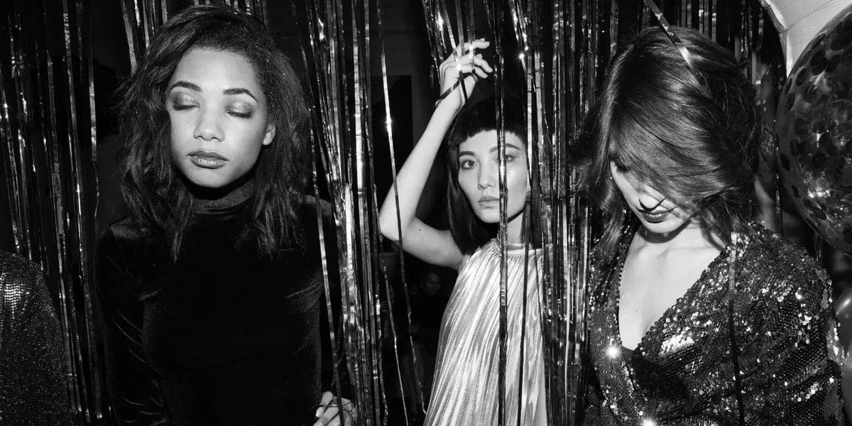 Trois femmes lors d'une soirée, portant des robes extravagantes.