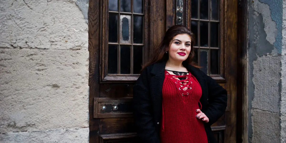 Femme à forte poitrine portant un soutien-gorge adhésif sous une robe en maille rouge.