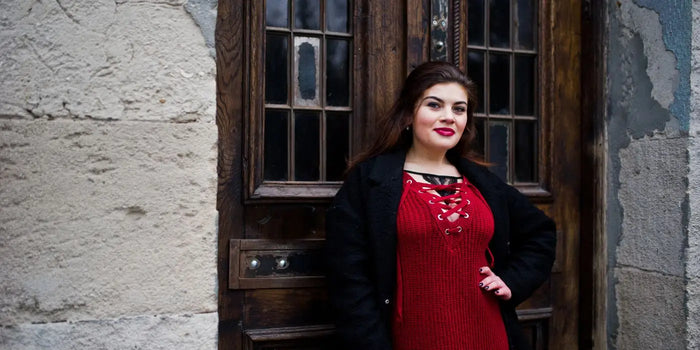 Femme à forte poitrine portant un soutien-gorge adhésif sous une robe en maille rouge.