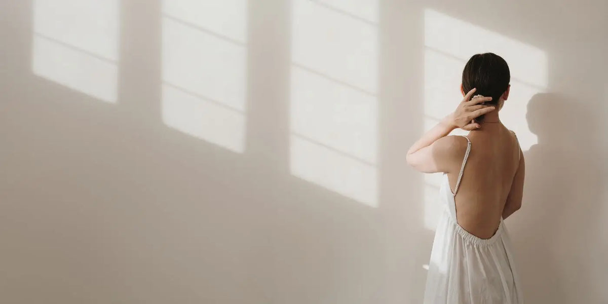 Femme portant une robe dos nu blanche.
