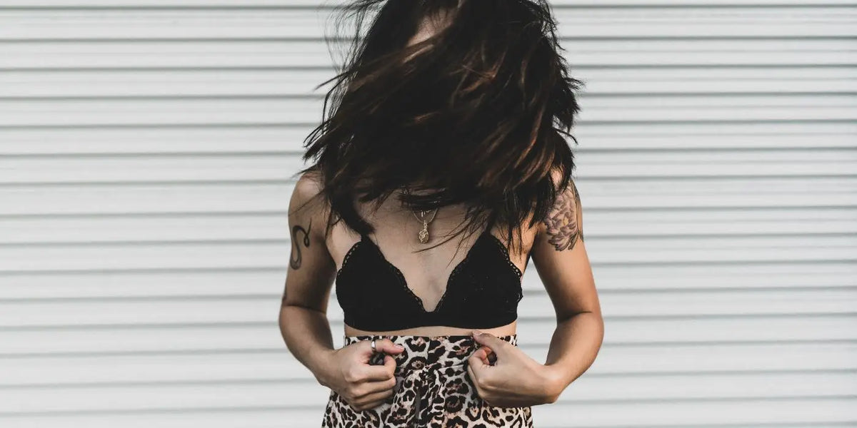 Femme à petite poitrine portant un soutien-gorge noir et un bas léopard.