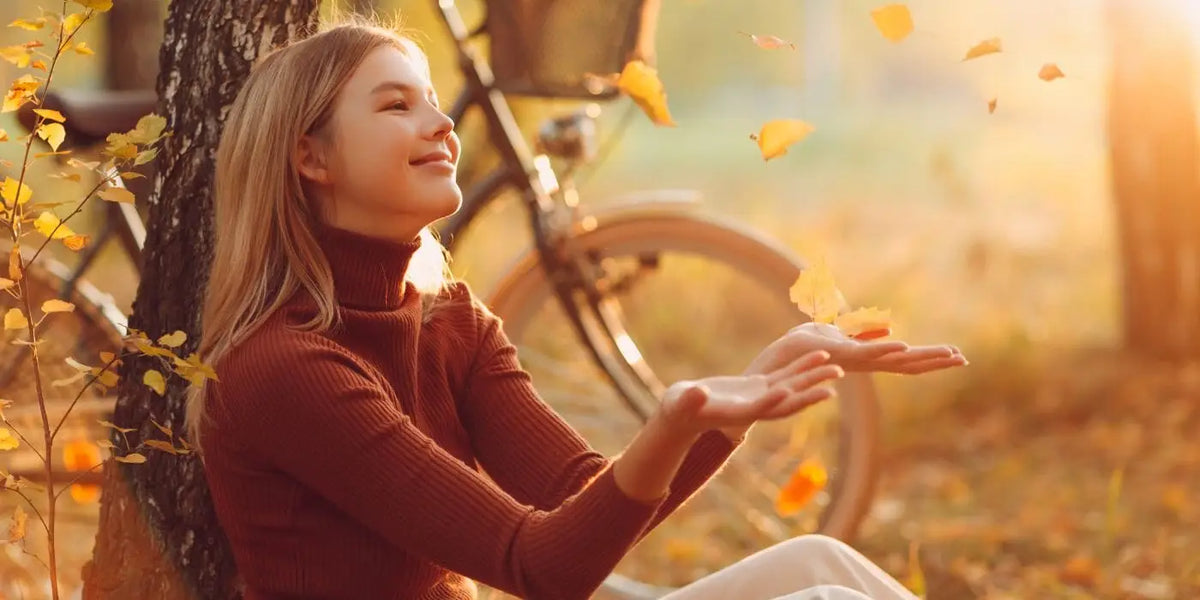 Femme colorimétrie automne assise dans les feuilles près de son vélo.
