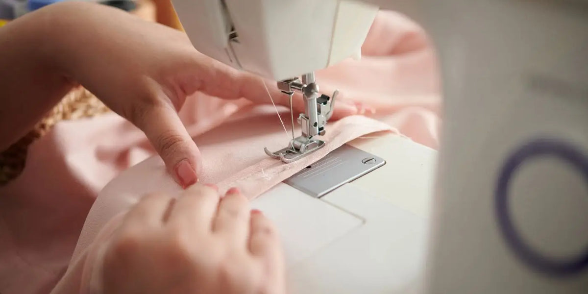 Femme rallongeant une robe avec une machine à coudre.