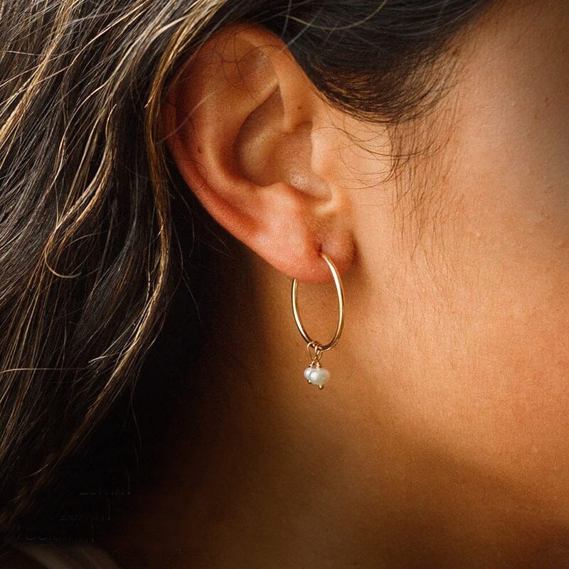 Boucles d'oreilles en or avec perles pendantes blanches portées, modèle Lucile, bijou élégant et raffiné.