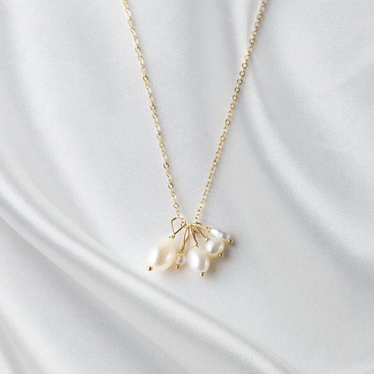 collier pendentif perles lucile, bijou élégant avec chaîne dorée et plusieurs perles blanches sur tissu blanc soyeux