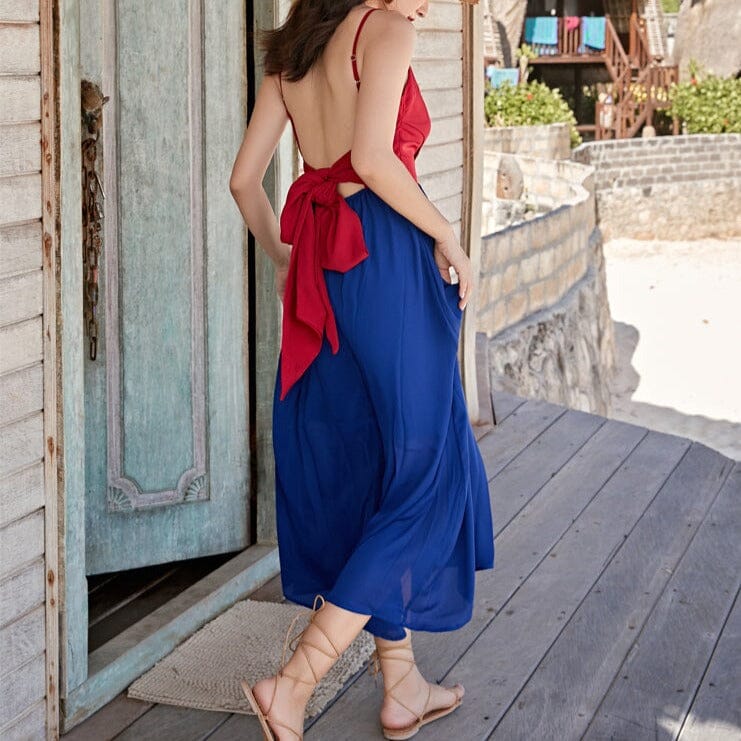 jeune femme portant une robe dos nu rouge et bleu nayla est en vacances à la plage devant une cabane en bois