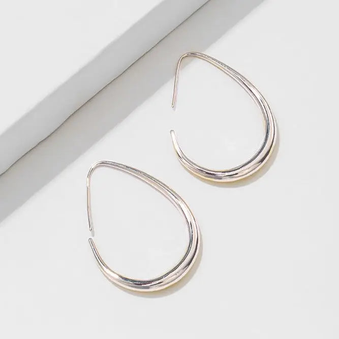 boucles d'oreilles créoles dorées élégantes en forme de goutte exposées sur un fond blanc lumineux, design minimaliste