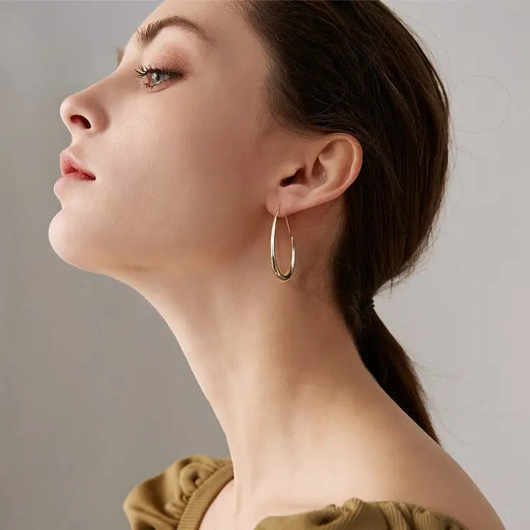 femme portant des créoles dorées élégantes, idéale pour les tenues décontractées et professionnelles