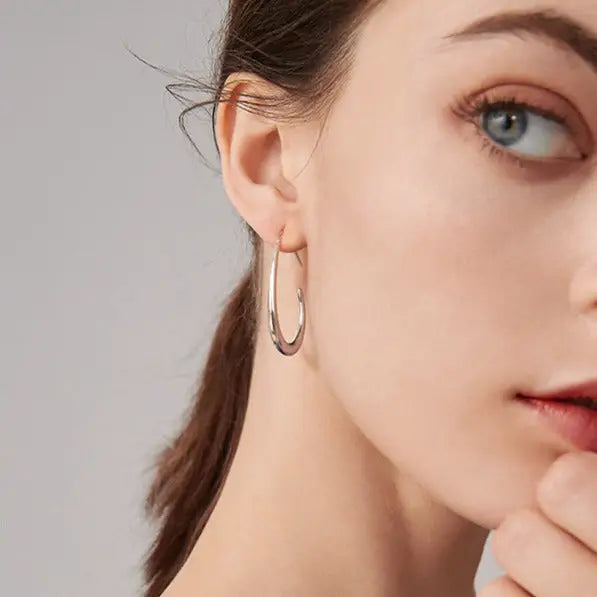 boucles d'oreilles créoles dorées portées par une femme, présentation détaillée du produit pour accentuer le style élégant