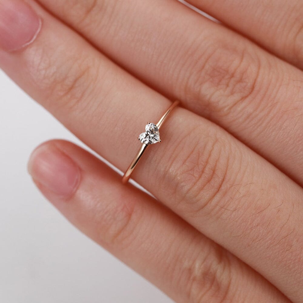 Bague en or avec un diamant en forme de cœur portée sur un doigt, collection Elsa de bijoux tendance et élégants.