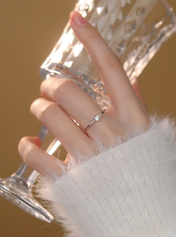 bague coeur diamant elsa délicate sur une main tenant un verre en cristal, parfaite pour une touche d'élégance.