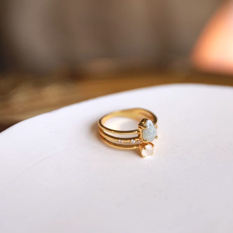 bague multirang en or avec plusieurs anneaux et pierres précieuses, posée sur un plateau blanc pour une présentation élégante