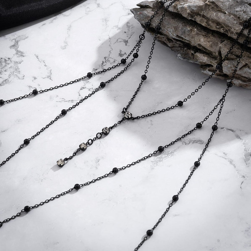bijou de corps pour femme sally avec chaînes et perles noires sur fond en marbre, accessoire élégant pour tenues féminines