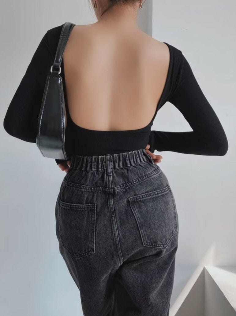 Body dos nu manches longues noir pour femme avec un sac à bandoulière noir et un jean taille haute gris foncé.