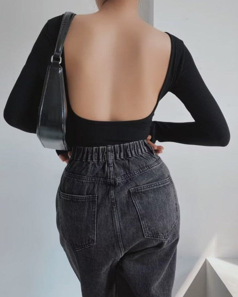 Body dos nu manches longues noir pour femme avec un sac à bandoulière noir et un jean taille haute gris foncé.