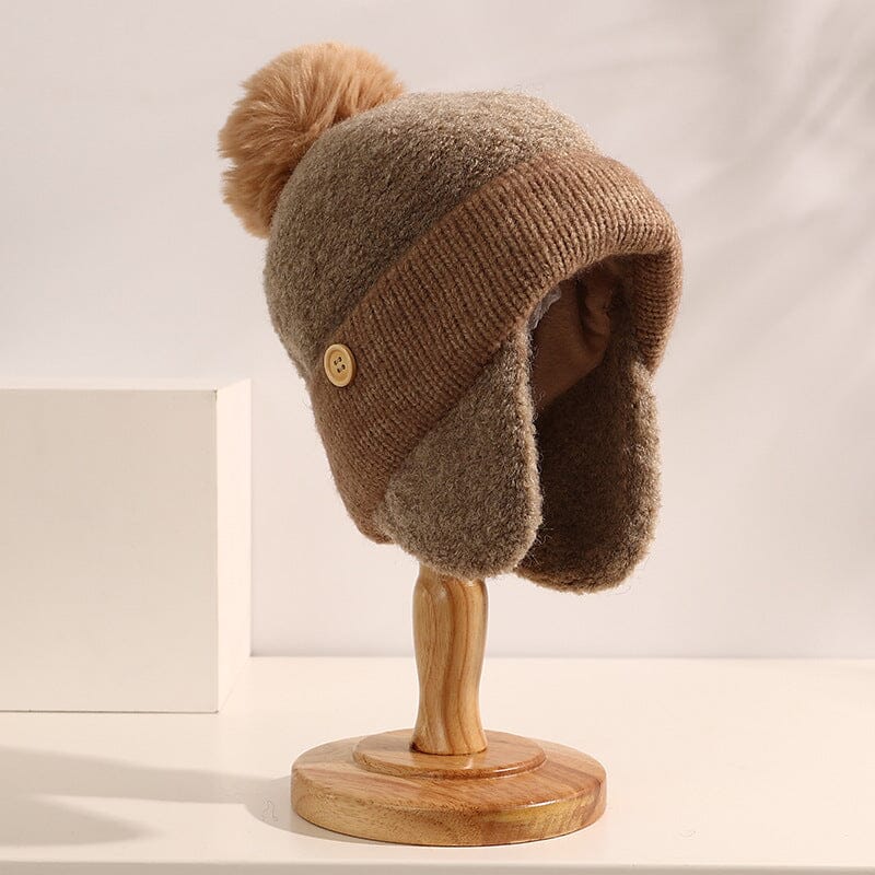 bonnet cache oreille pour femme beige avec pompon et bouton sur support en bois, modèle nina pour hiver et froid extrême