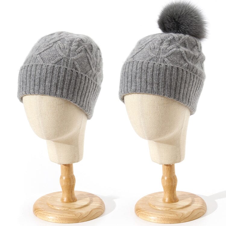 bonnets en cachemire gris pour femme avec pompon et motif géométrique sur des mannequins en bois