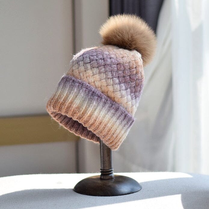 bonnet multicolore en laine laeticia avec pompon en fourrure marron exposé sur un présentoir dans une pièce éclairée