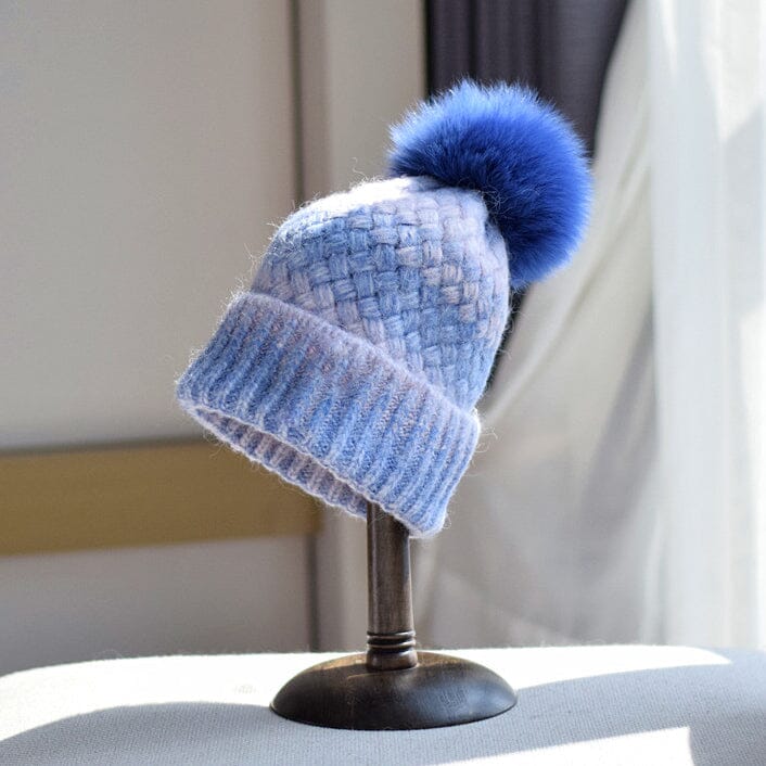 bonnet multicolore en laine laeticia avec pompon bleu, exposé sur un présentoir dans une pièce lumineuse