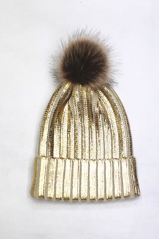 Bonnet pailleté doré avec pompon en fausse fourrure, modèle Lucie, pour un style élégant et lumineux en hiver.