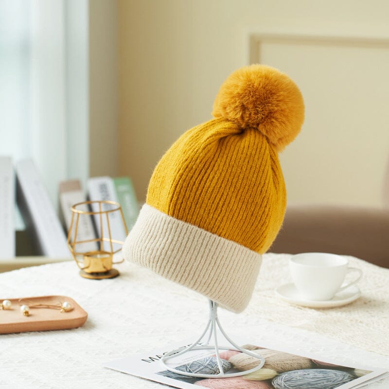 bonnet polaire pauline jaune avec un ourson en peluche sur une table, parfait pour les journées froides d'hiver