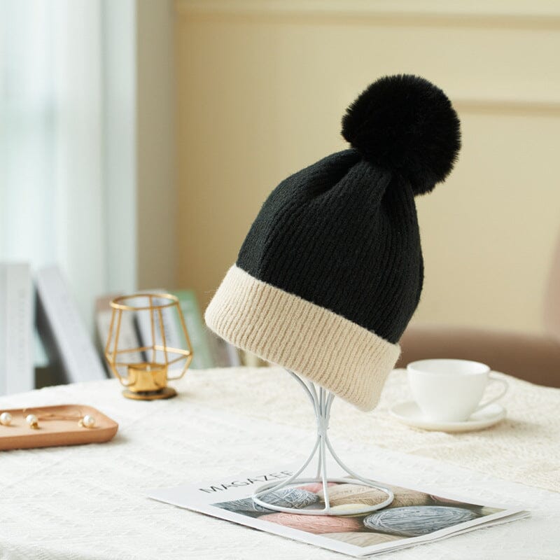 bonnet polaire noir avec bord beige pour femme, modèle pauline, sur table avec décor moderne, tasse et magazines